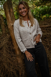 Gilet boutonné à poches beige porté par une femme, vue de face, forêt, sourire