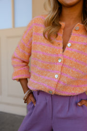 Gilet doux légèrement ample porté par une femme, gros plan de la maille rayée