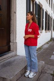 Gilet ample boutonné rouge porté par une femme, vue de face, jean, baskets blanches