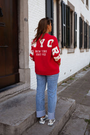 Gilet ample boutonné rouge porté par une femme, vue de dos, lettres blanches, jean
