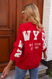 Gilet ample boutonné rouge porté par une femme, vue de dos, lettres blanches, porte en bois, autre cadrage