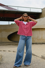 Gilet boutonné manches courtes porté par une femme, silhouette entière, lunettes de soleil, mains levées