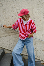 Gilet boutonné manches courtes porté par une femme, vue de trois-quarts, casquette rose, sur des escaliers