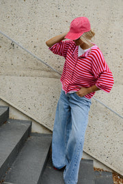 Gilet boutonné manches courtes porté par une femme, silhouette entière, casquette rose, sur des escaliers