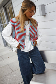 Gilet sans manches à poches porté par une femme, vue de trois-quarts, cheveux longs, chaise blanche