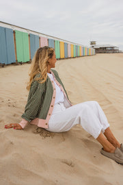 Gilet éponge rayé à pressions porté par une femme, assise, sable, pantalon blanc