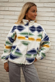 Gilet polaire zippé à motifs écru porté par une femme, vue de trois-quarts, col montant, mur blanc