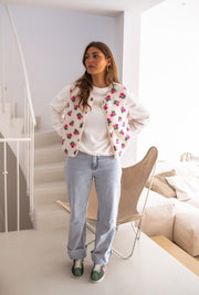 Gilet fleuri effet mouton porté par une femme, vue de face, escalier blanc, fauteuil en rotin