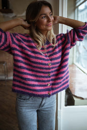 Gilet rayé à boutons cœur porté par une femme, vue rapprochée, mains dans les cheveux, boutons