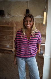Gilet rayé à boutons cœur porté par une femme, vue de face, sourire, jean clair