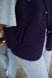Gilet mouton court sans manches mauve porté par une femme, vue rapprochée, gilet violet, t-shirt gris