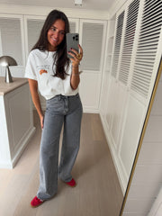 T-shirt à logo croissant blanc porté par une femme, vue de face, selfie au miroir, jean gris