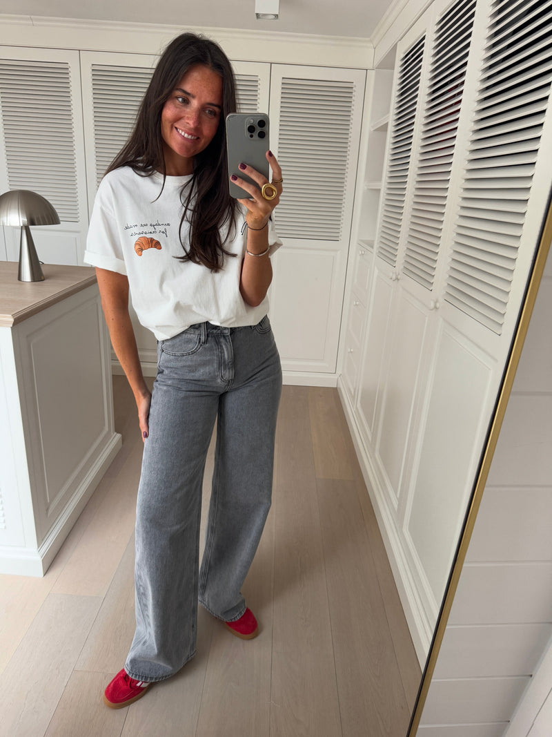 T-shirt à logo croissant blanc porté par une femme, vue de face, selfie au miroir, jean gris