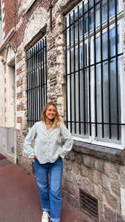 Chemise rayée à manches bouffantes portée par une femme, silhouette entière, mur de briques, jean