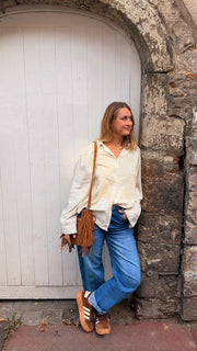 Chemise en lin brodée portée par une femme, silhouette entière, porte blanche, sac