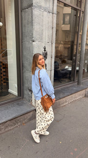 Chemise à col volanté portée par une femme, silhouette entière, rue, pantalon à pois, de côté