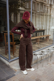 Jean ample coupe ballon porté par une femme, silhouette entière, casquette bordeaux, terrasse