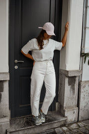 Jean coupe mom légèrement loose porté par une femme, vue de trois-quarts, porte noire, casquette