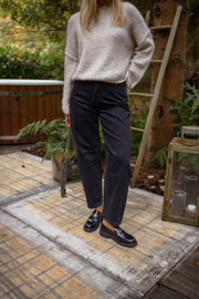Jeans mom coupe loose porté par une femme, vue de trois-quarts, pull gris, terrasse