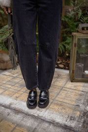 Jeans mom coupe loose porté par une femme, vue rapprochée, mocassins noirs, jean gris foncé
