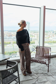 Jean taille haute à motifs porté par une femme, silhouette entière, sac, terrasse