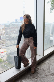 Jean taille haute à motifs porté par une femme, silhouette entière, sac, fenêtre