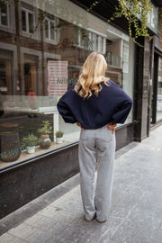 Jean flare taille haute porté par une femme, vue de dos, pull marine, trottoir