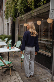 Jean flare taille haute porté par une femme, silhouette entière, terrasse, pull marine