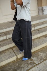 Jeans large effet ballon porté par une femme, vue de dos, t-shirt blanc, escalier