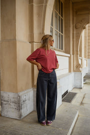 Jeans large effet ballon porté par une femme, silhouette entière, haut bordeaux, colonnes