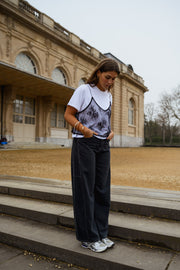 Jeans large effet ballon porté par une femme, silhouette entière, haut à bretelles, escalier