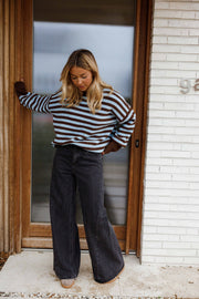 Jean large à coupe loose porté par une femme, silhouette entière, haut rayé, porte