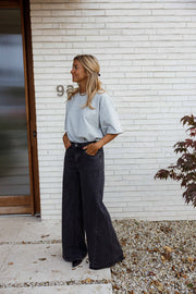 Jean large à coupe loose porté par une femme, silhouette entière, haut bleu clair, porte