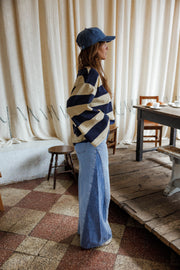 Jean large à côtés bicolores porté par une femme, vue de profil, casquette, pull rayé