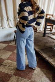 Jean large à côtés bicolores porté par une femme, silhouette entière, pull rayé, de face