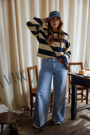 Jean large à côtés bicolores porté par une femme, silhouette entière, main sur la casquette