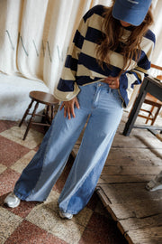 Jean large à côtés bicolores porté par une femme, silhouette entière, pull rayé, casquette