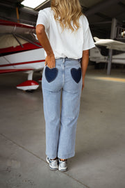 Jeans taille haute extensible porté par une femme, vue de dos, poches cœur, hangar