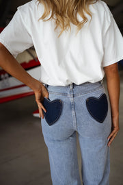 Jeans taille haute extensible porté par une femme, vue rapprochée, poches en forme de cœur