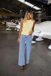 Jeans taille haute extensible porté par une femme, silhouette entière, hangar, avion