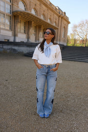 Jeans à étoiles perlées évasé porté par une femme, silhouette entière, lunettes, foulard bleu