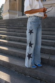 Jeans à étoiles perlées évasé porté par une femme, vue rapprochée, étoiles, mains dans les poches