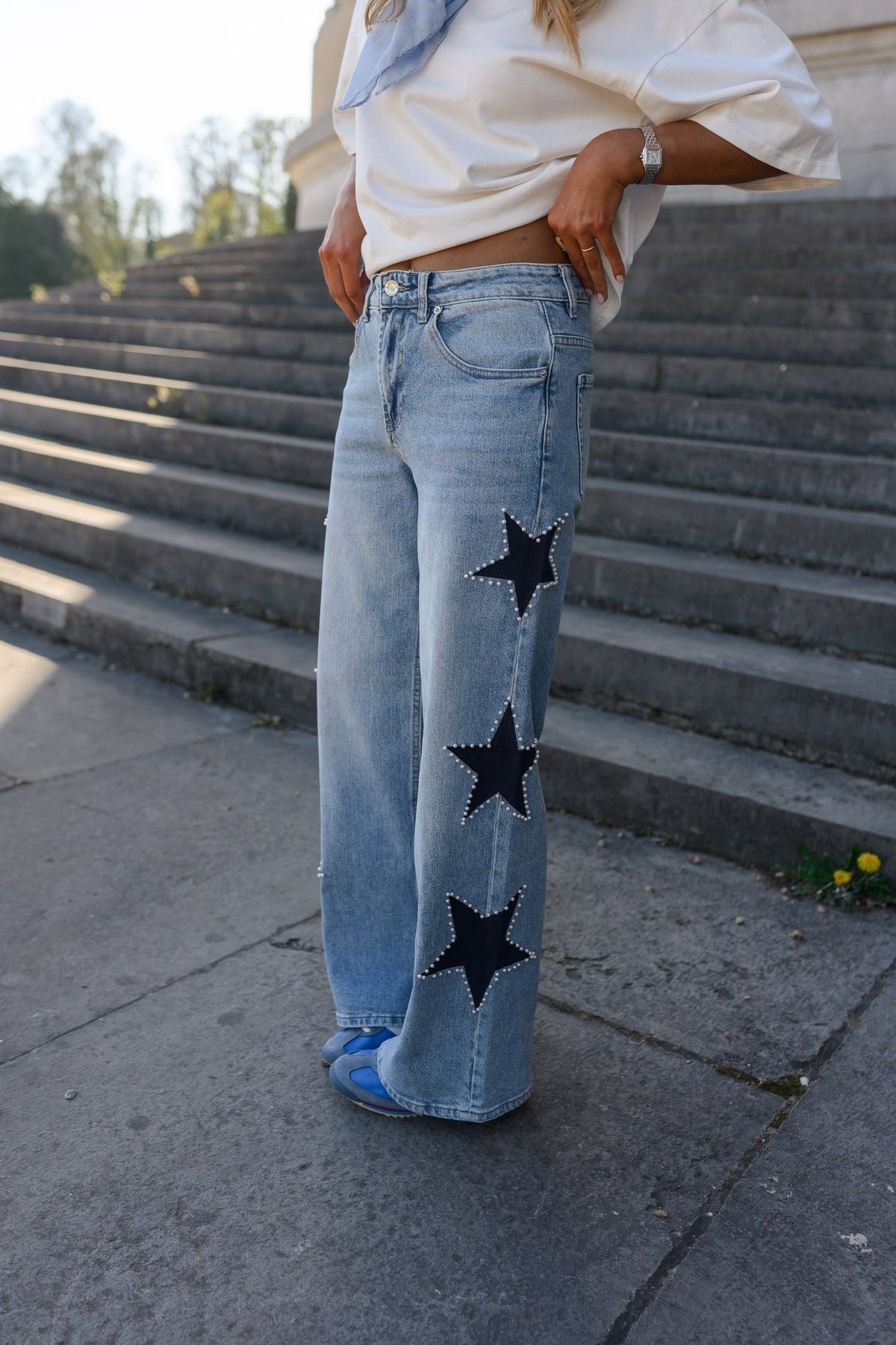 Jeans à étoiles perlées évasé porté par une femme, silhouette entière, étoiles, escalier