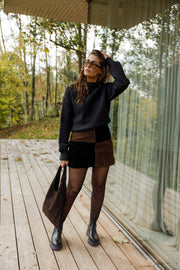 Jupe en daim à damier portée par une femme, silhouette entière, sac, collants, terrasse