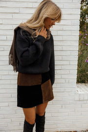 Jupe en daim à damier portée par une femme, vue rapprochée, pull noir, cheveux blonds