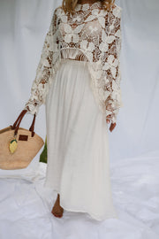 Jupe longue fluide doublée beige portée par une femme, silhouette entière, blouse en dentelle, panier