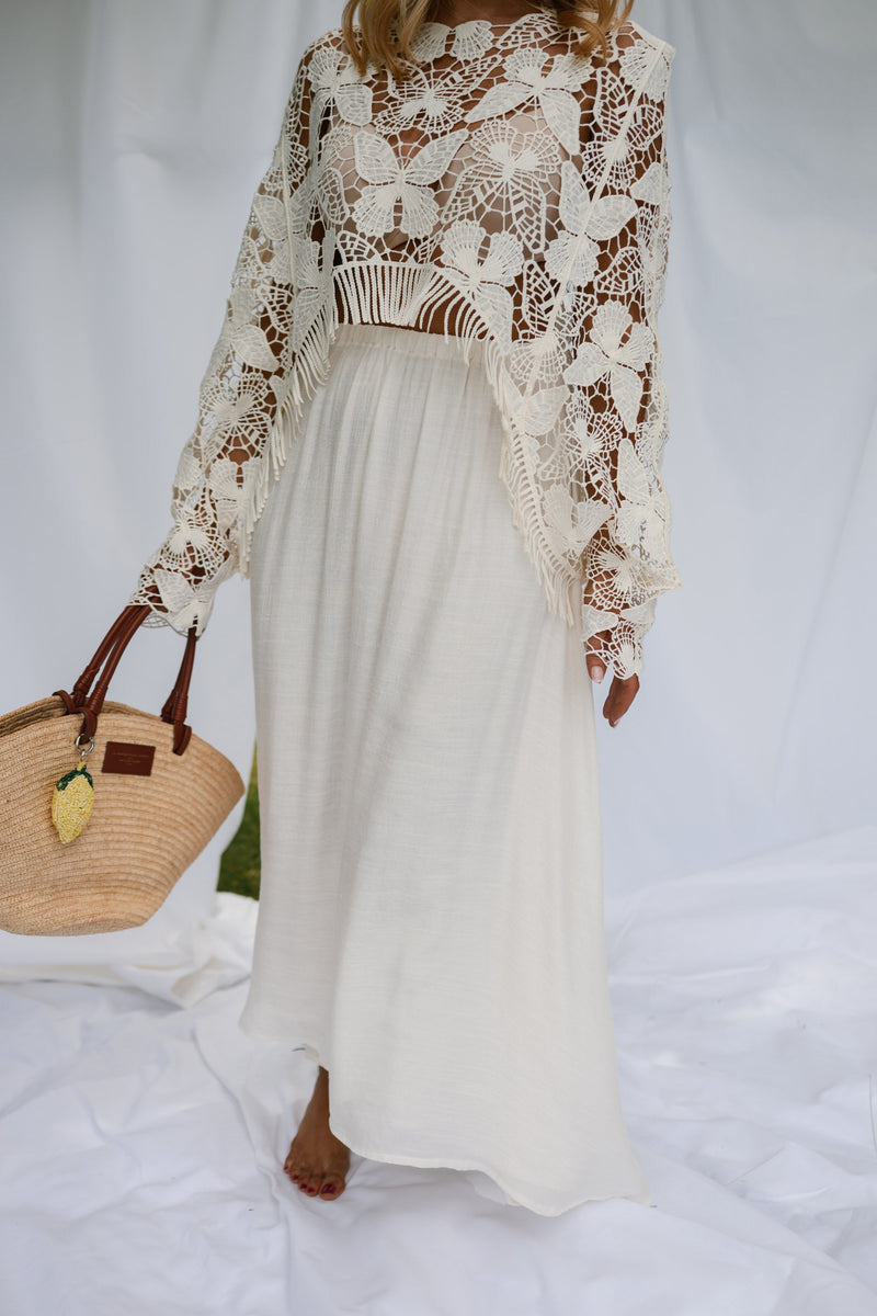 Jupe longue fluide doublée beige portée par une femme, silhouette entière, blouse en dentelle, panier