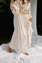 Jupe longue fluide doublée beige portée par une femme, en marchant, jupe en mouvement, blouse en dentelle