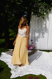 Jupe longue fluide doublée jaune portée par une femme, silhouette entière, drapés, camisole blanche