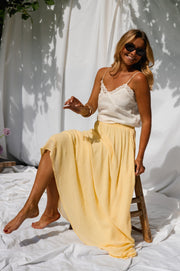 Jupe longue fluide doublée jaune portée par une femme, assise, drapés blancs, jupe jaune